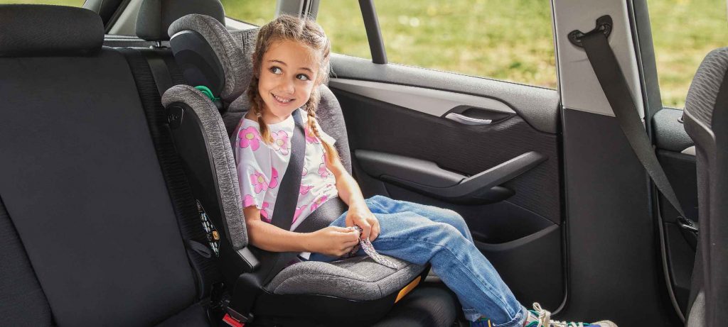 Niña de seis años viajando en silla infantil de coche Colosso i-size de color gris melange
